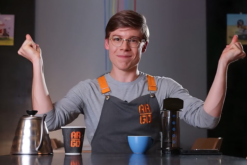 Still image of a presenter clicking their fingers as they teach how to make coffee in an Adelaide training film